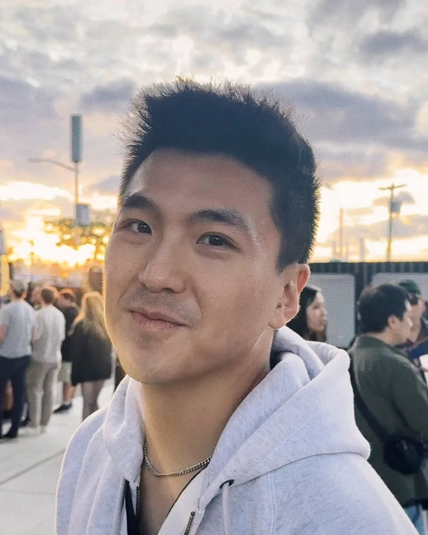 Kelvin smiling at an outdoor festival at golden hour