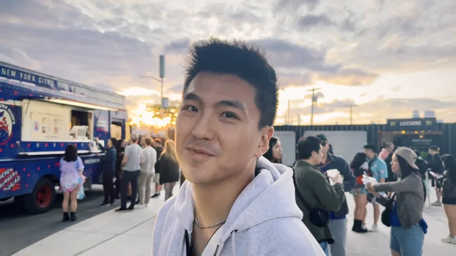 Kelvin smiling at an outdoor festival at golden hour