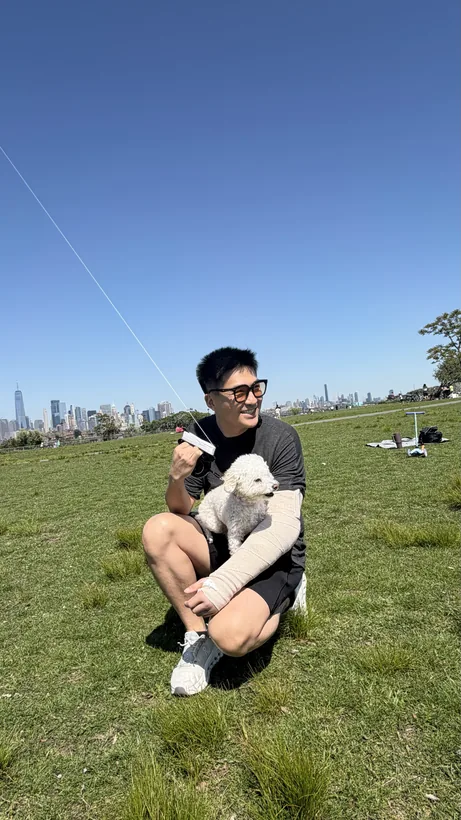 暖暖 with Kelvin on the grass, the New York skyline behind, May 2026